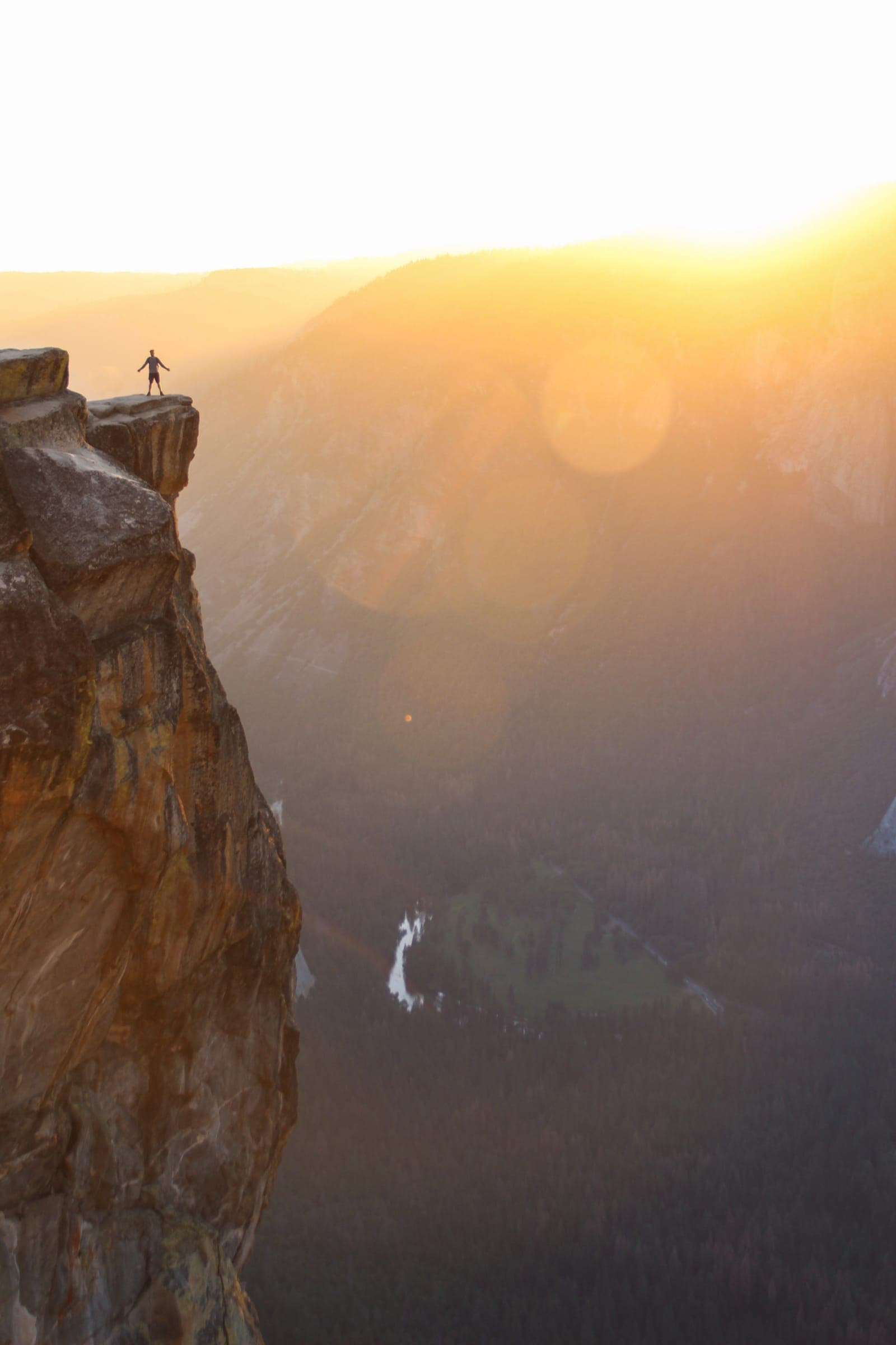 A climber ascending a rock face into the morning sun