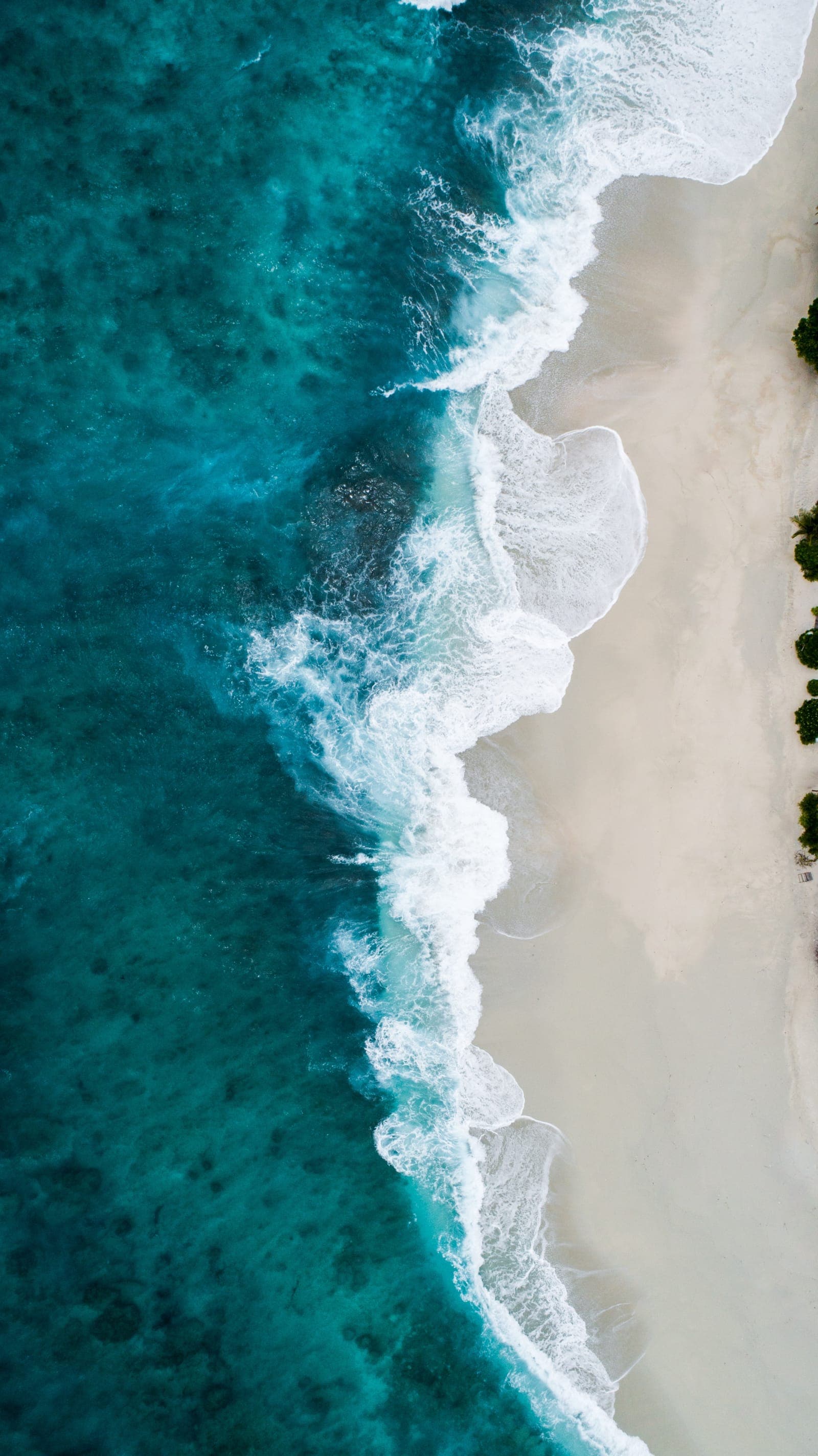 Aerial view of surf meeting a turquoise coastline