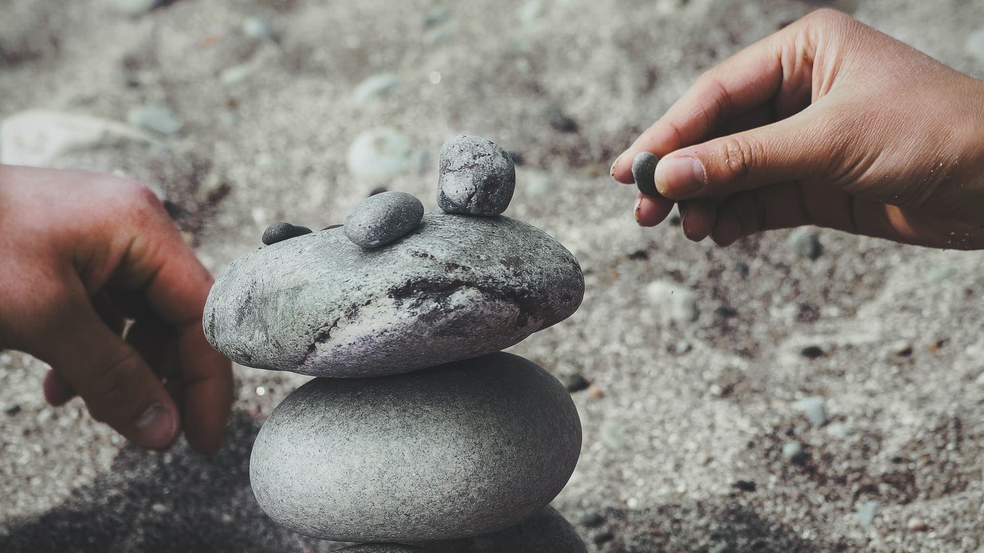 Hands carefully balancing a stack of stones