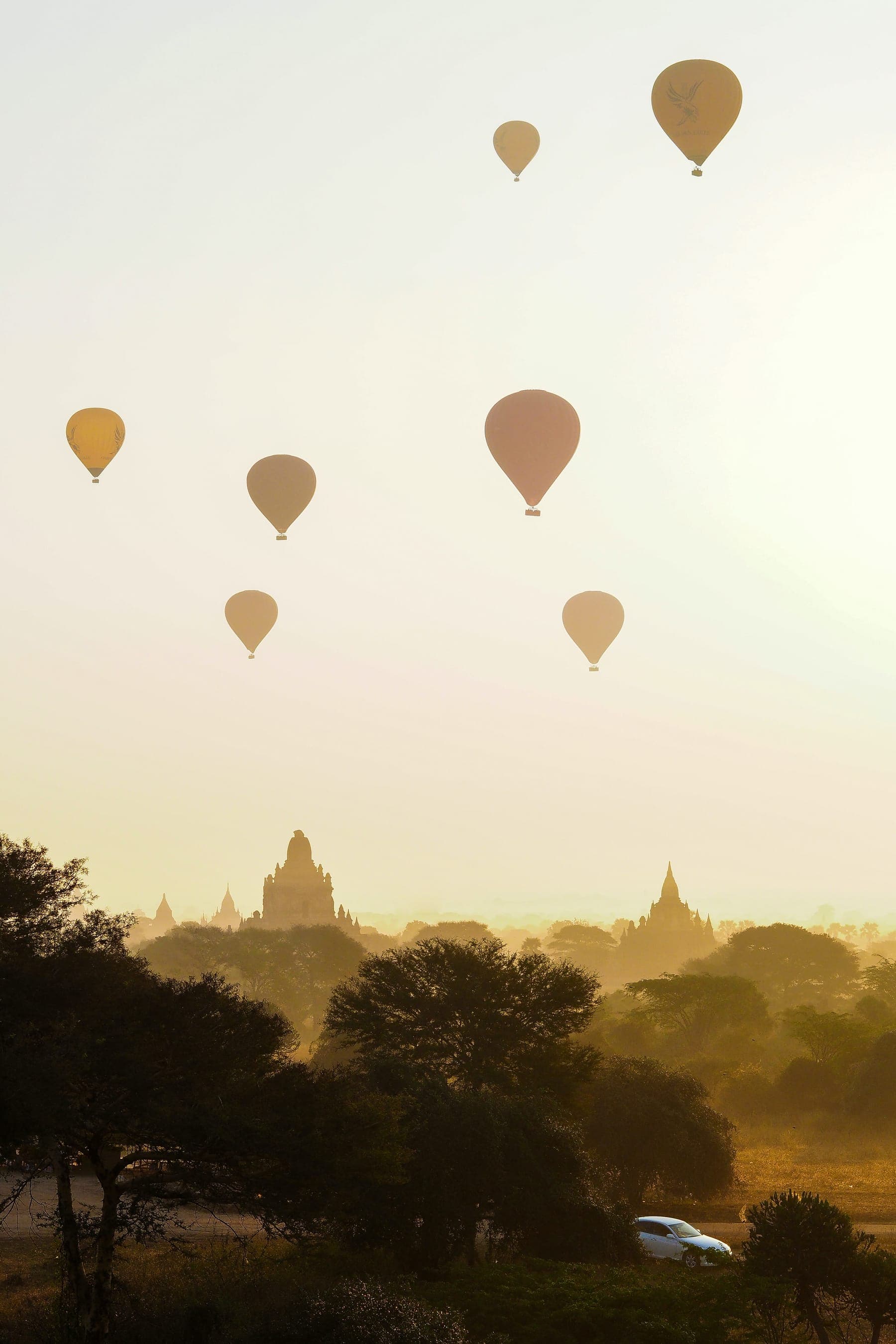 Hot-air balloons drifting over an ancient landscape at dawn