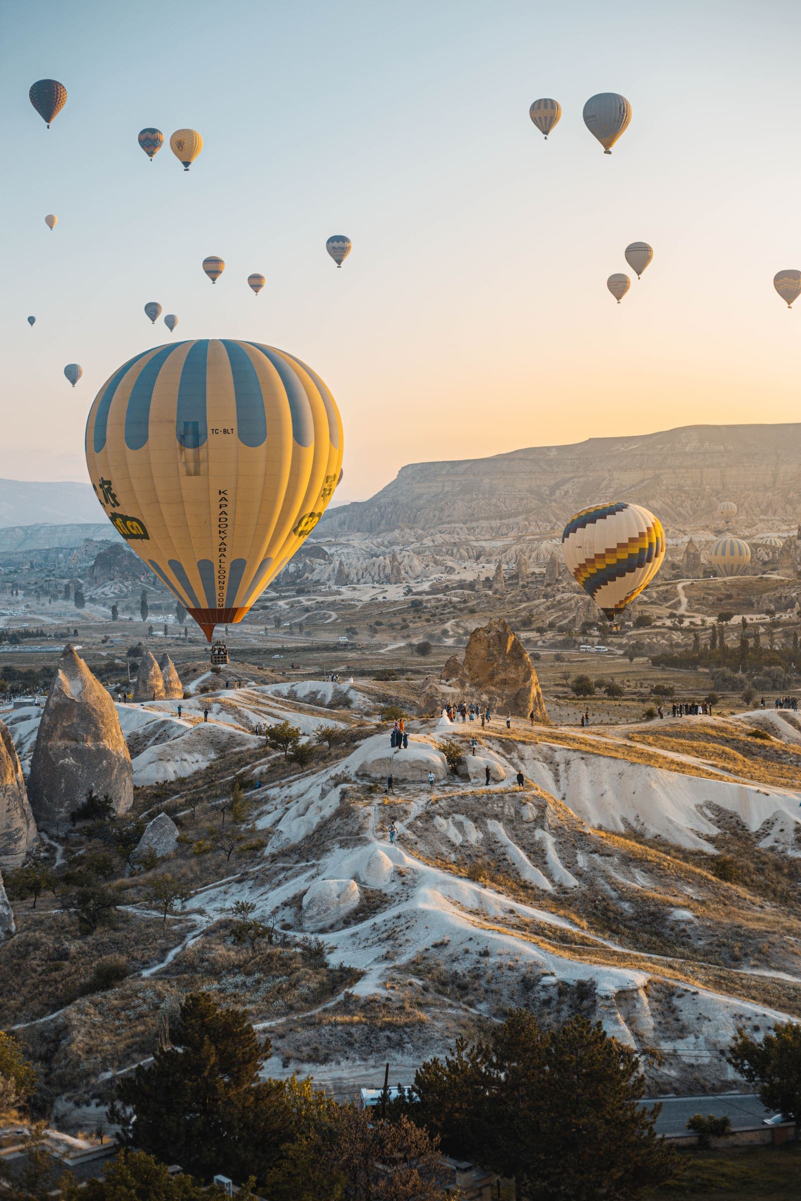 A hot-air balloon rising over a sweeping valley at dawn